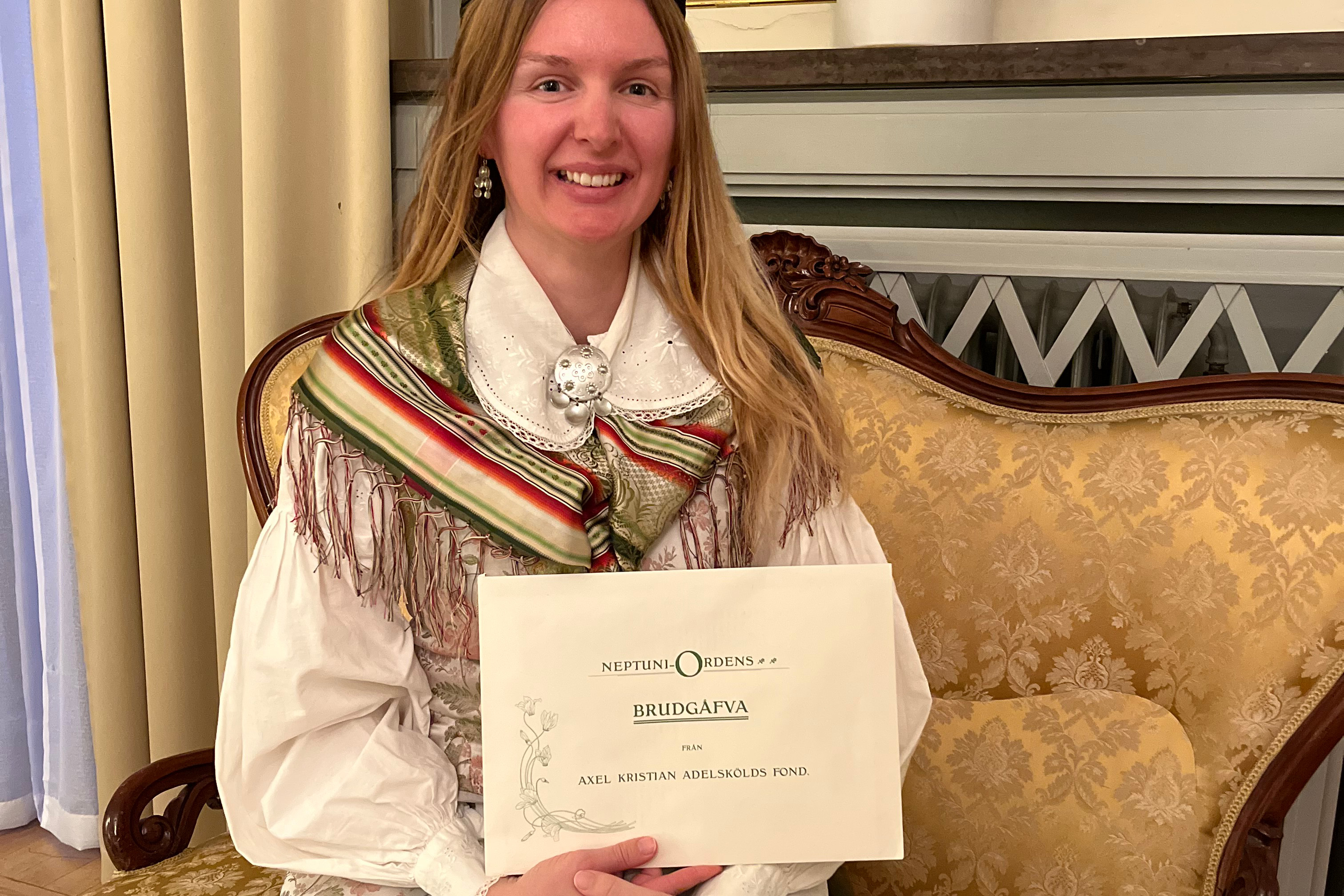 Kvinna sitter i en soffaoch håller i ett brev.