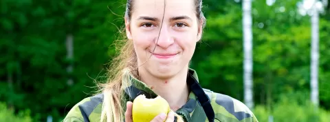 Kvinna i uniform som håller ett äpple i handen