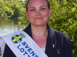 kvinna utomhus med ett värdinneband över axeln